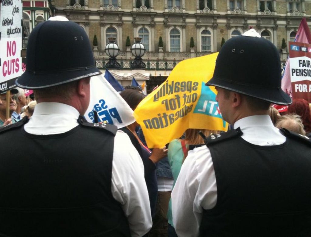 Two policemen watch the march during an earlier public sector strike.