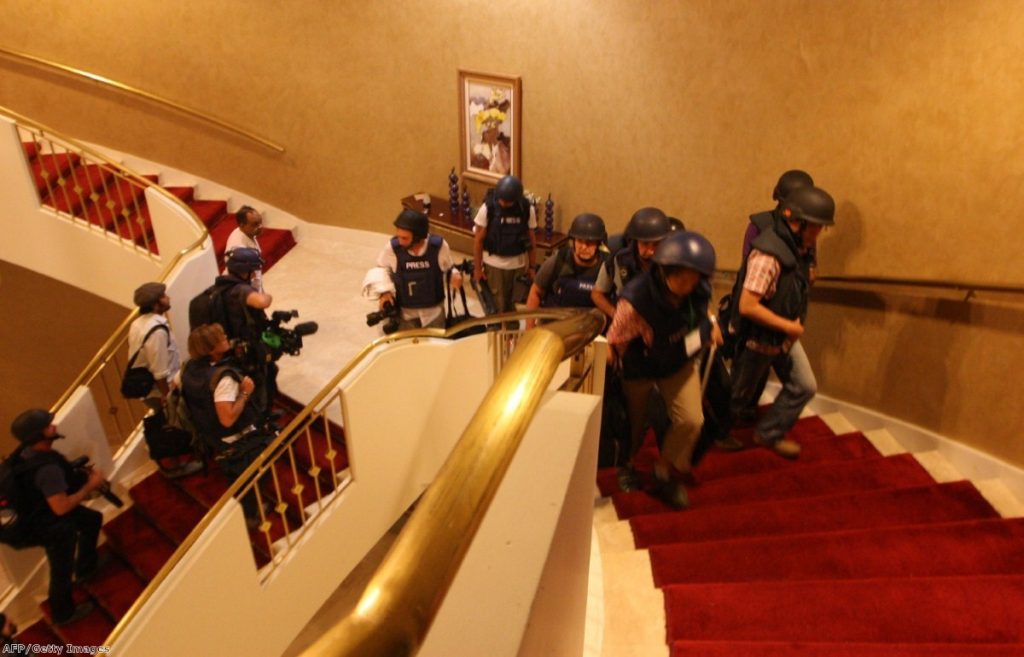 Foreign journalists in protective gear climb the stair at the Rixos hotel where they were confined.