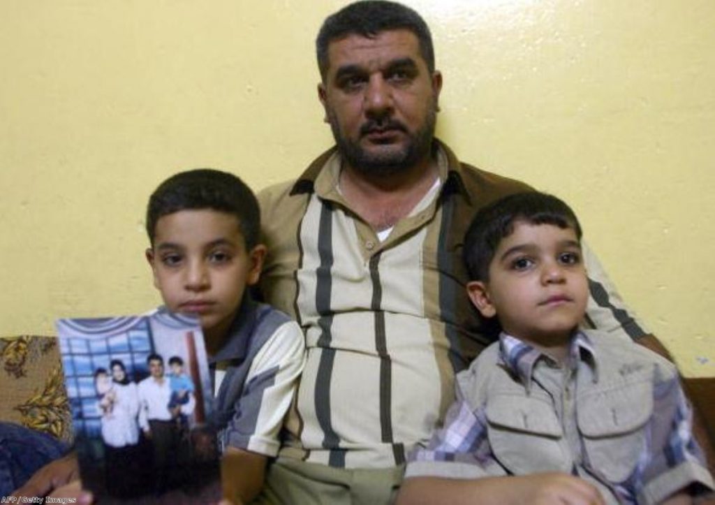 Baha Mousa's family: Hassan holds a family photo as he sits with uncle Alaa and younger brother Ali at their home in Basra