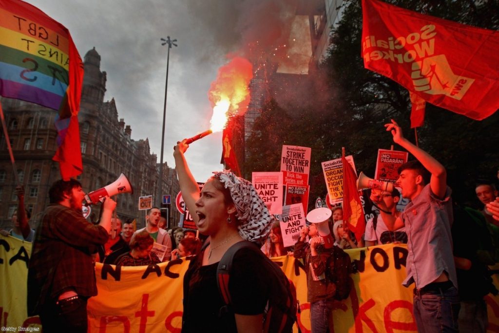 A demonstrator lights a flare during the march in Manchester.