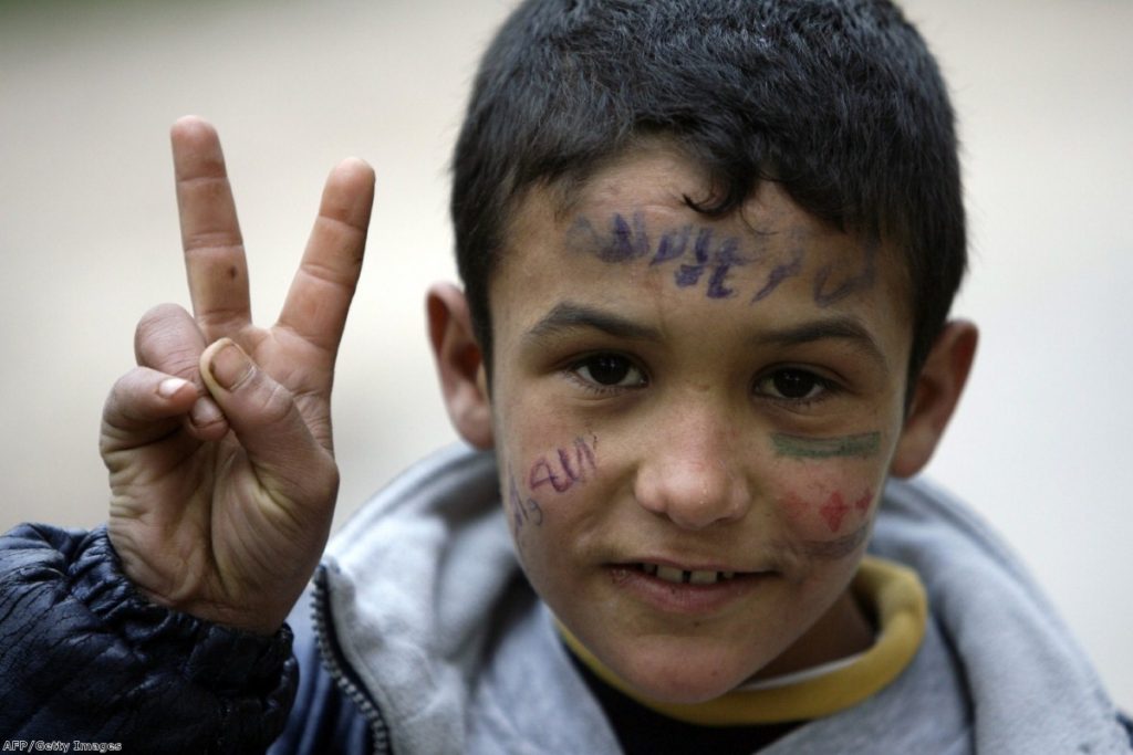 A young Syrian refugee fleeing violence in Homs flashes the 'V for Victory' sign