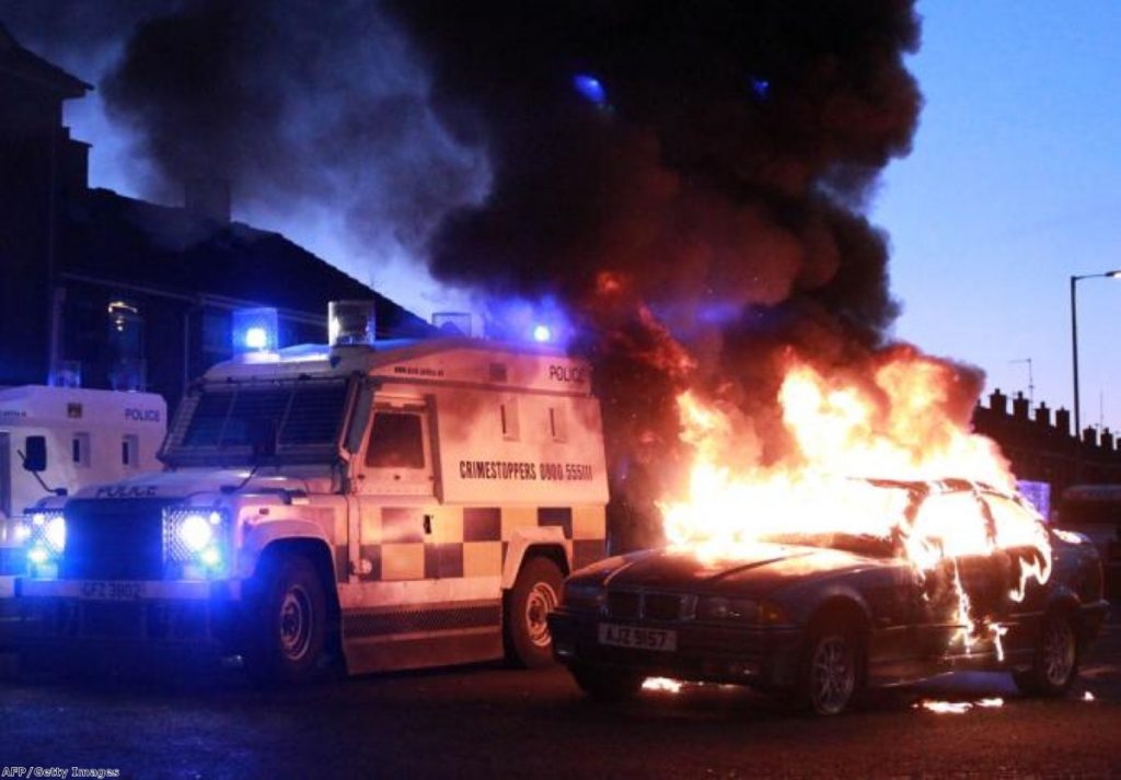 Police attend a burning vehicle in Belfast unrest caused by the flag decision