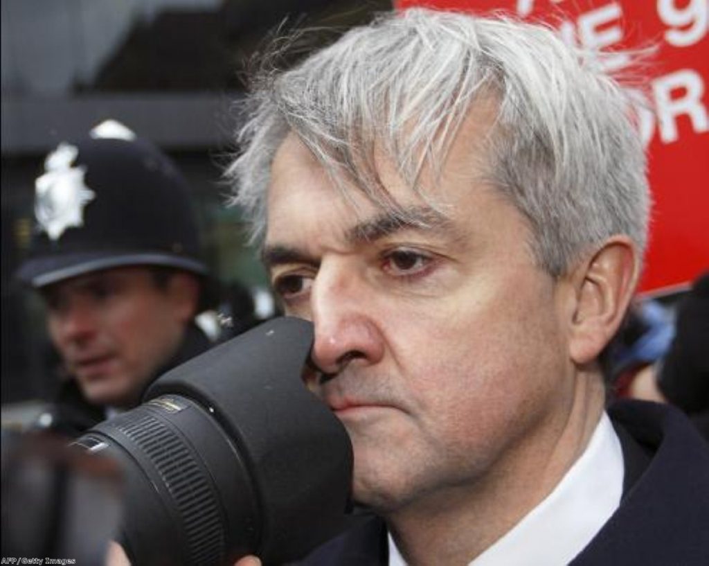 Chris Huhne arrives in court amid a media scrum today