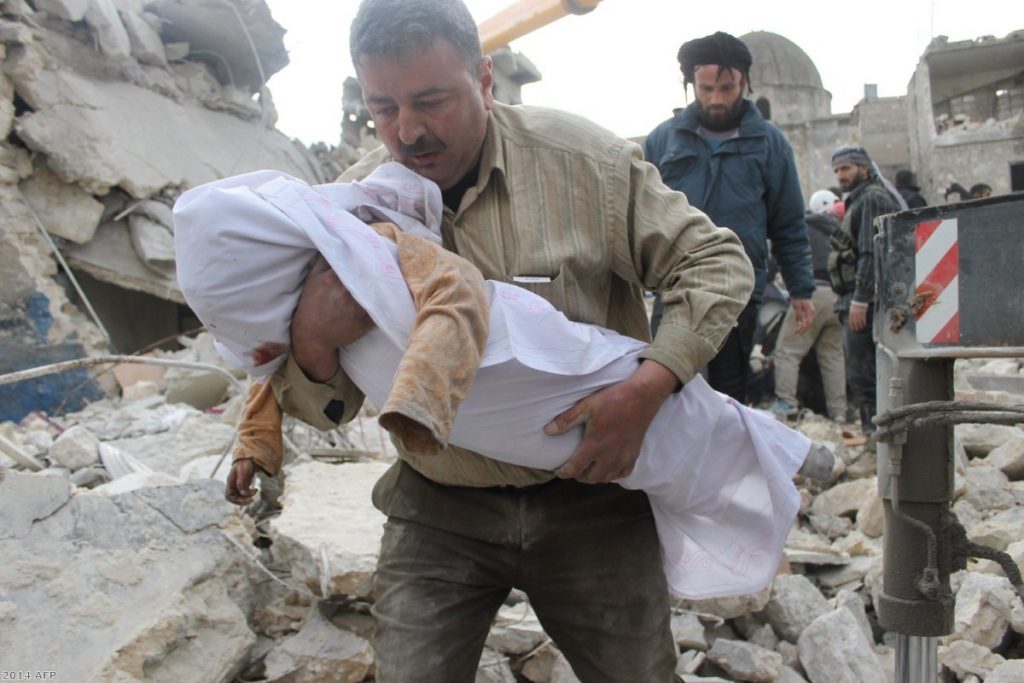 A Syrian man carries a body out of the rubble following air raids by government forces