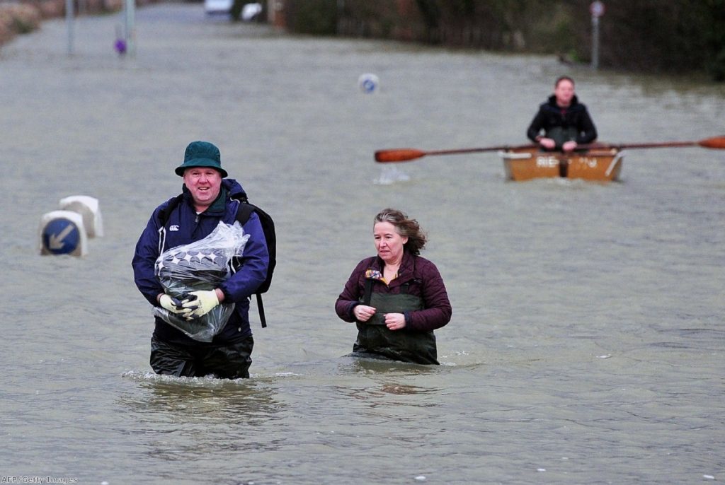 A couple wade along a flooded road near Egham, west of London, yesterday.