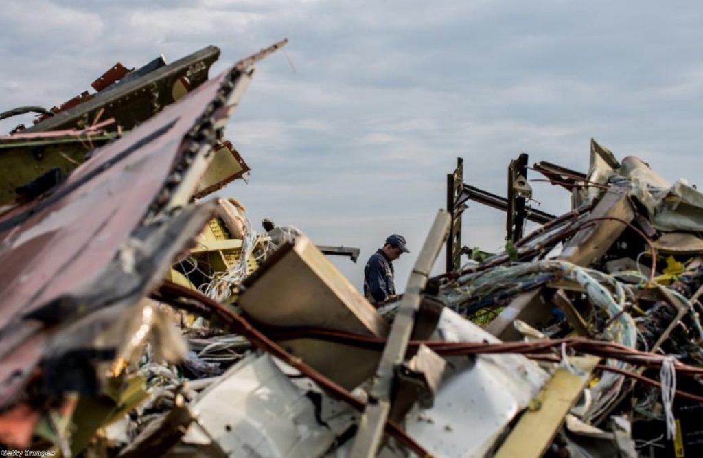 A man inspects the debris at the site of the downed MH17 aircraft