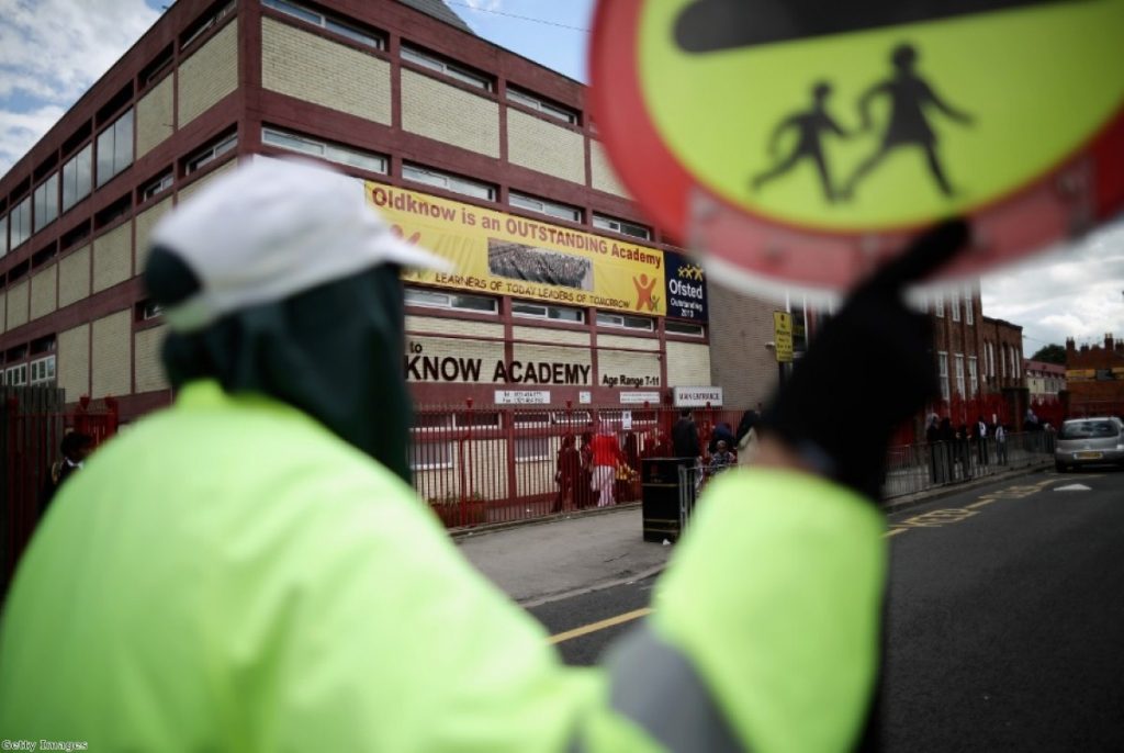A lollipop person looks on at one of the Birmingham schools implicated in the Trojan Horse plot