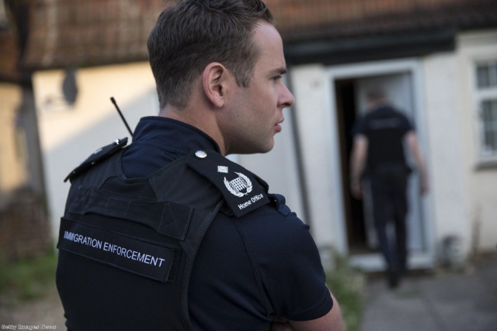 An immigration officer takes part in a raid on suspected undocumented migrants. Lawyers say up to 20 officers attend dawn raids against their clients.