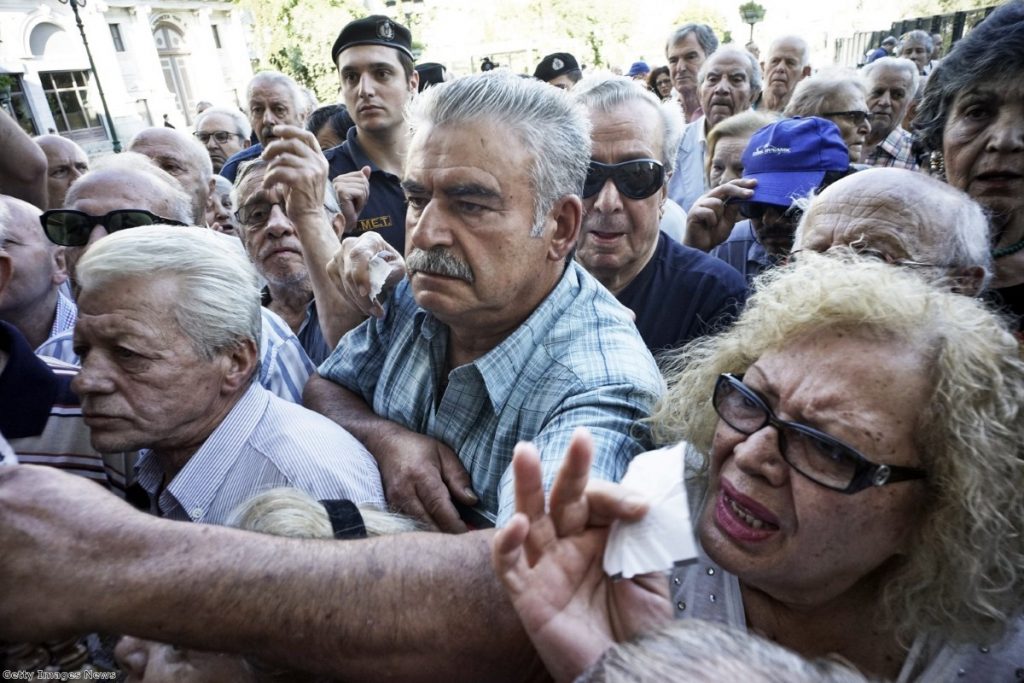 Pensioners line up outside a National Bank branch in Athens yesterday after they open to allow them a small part of their benefits