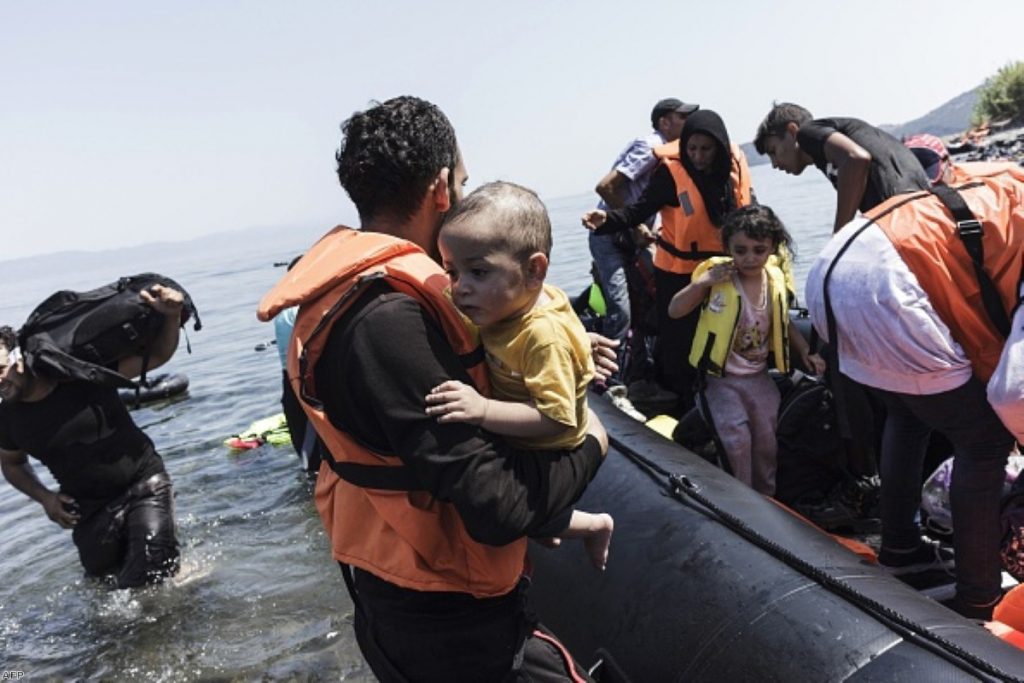 Family arrives on Greek beach, after crossing, on an inflatable boat with 35 people