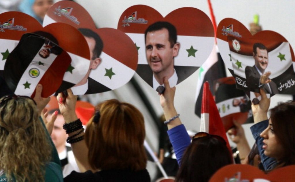 Assad supporters wave flags and placards during last year's presidential elections