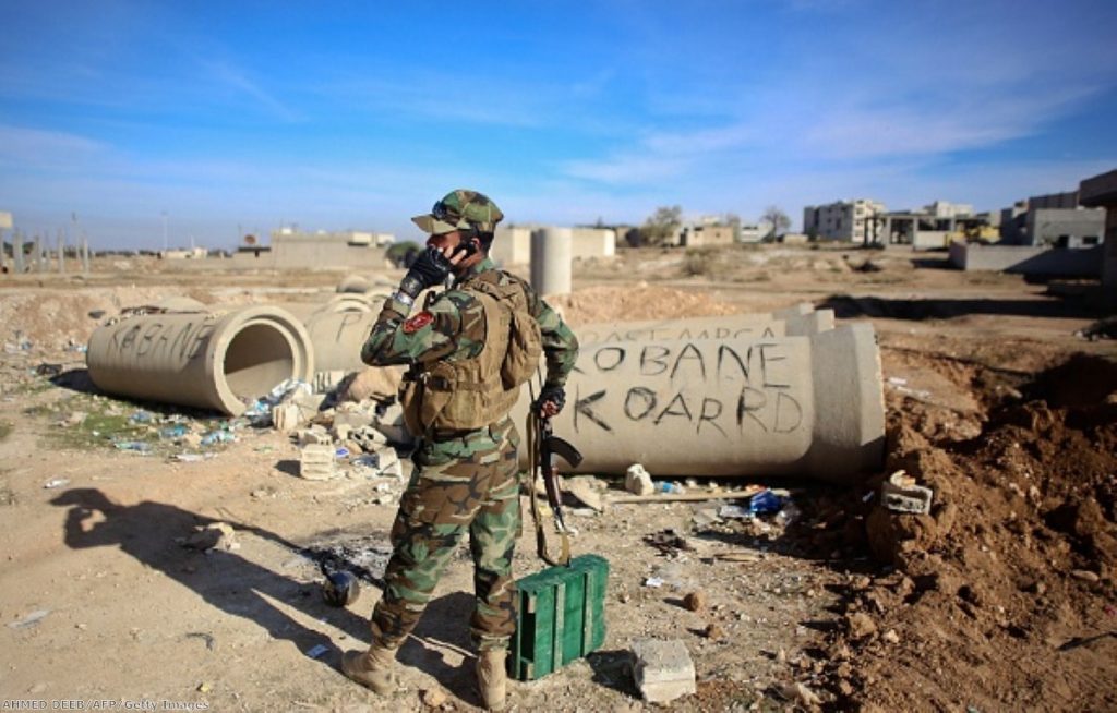 A Kurdish Peshmerga fighter talks on the phone during fighting against Islamic State