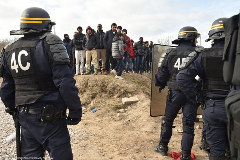 Anti-riot police face migrants during the dismantling of half of the 'Jungle' migrant camp in Calais