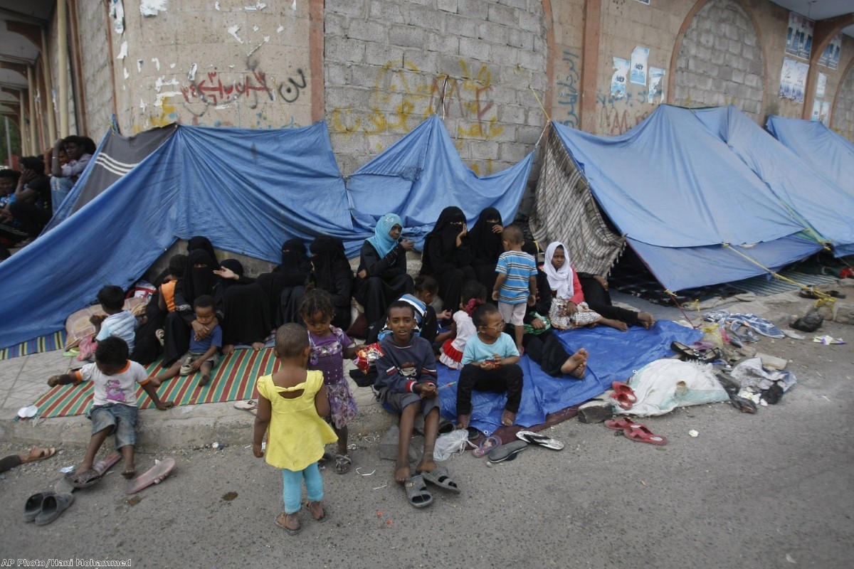 Eritrean female asylum seekers sit along with their children on the sidewalk in Yemen
