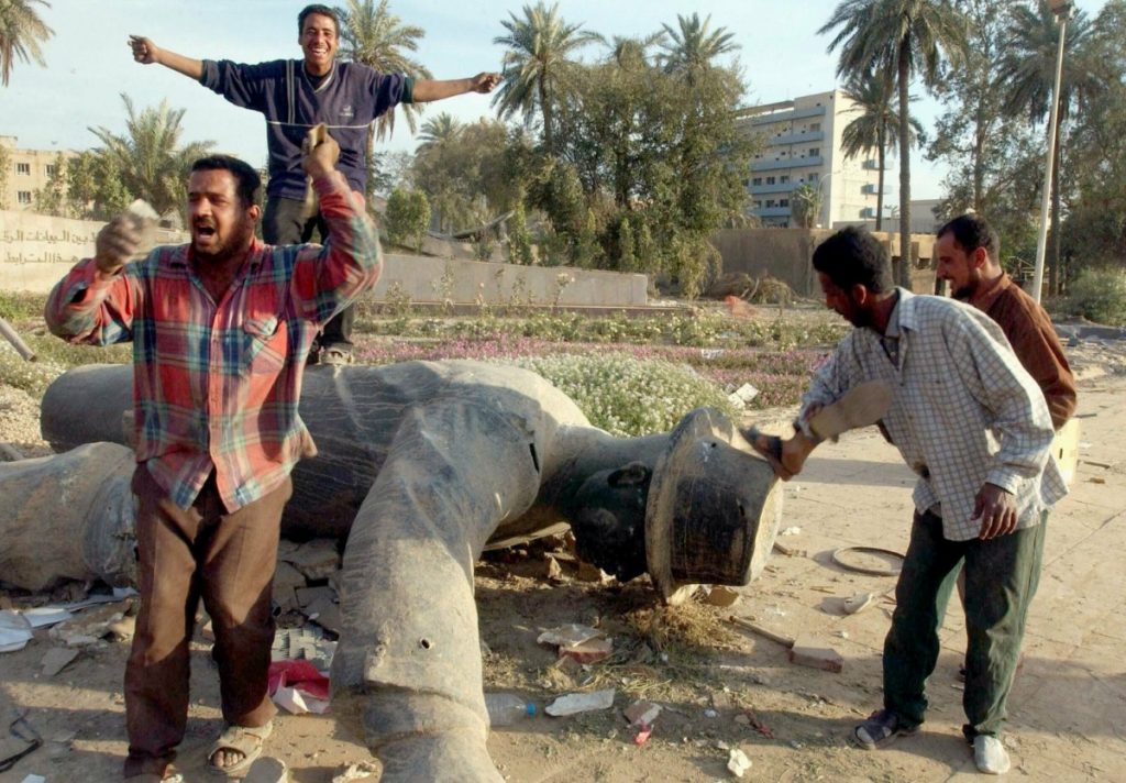 Iraqis celebrate around a toppled statue of Saddam Hussein on April 12th 2003.