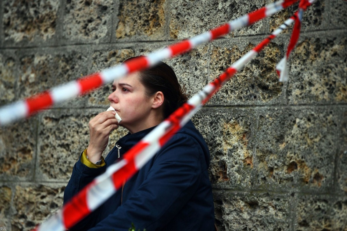 An onlooker in Paris wipes away a tear at a police cordon line near the Notre Dame Cathedral yesterday.