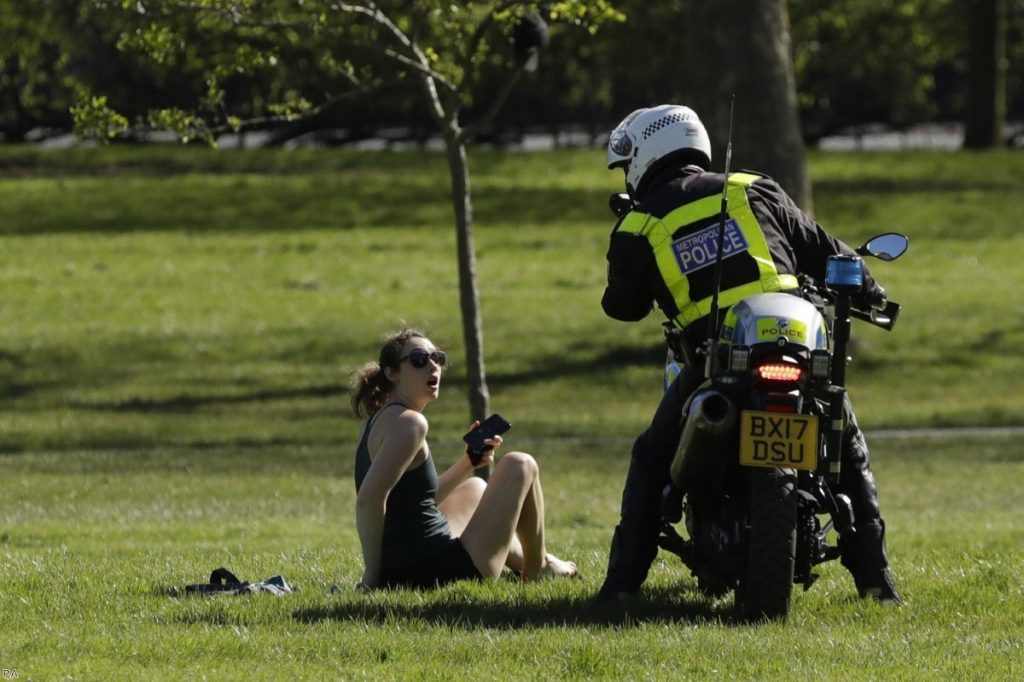 A woman is told to go home by a police officer on Primrose Hill in London last weekend.