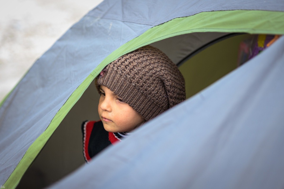 A young girl from Syria, who is on the run with her family, looks out of a tent in the Turkish border town of Edirne, near the Pazarkule-Kastanies border crossing, last spring.